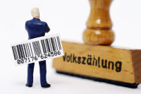Miniaturfigur mit Strichcode vor einem Stempel mit dem Schriftzug Volksz�hlung.