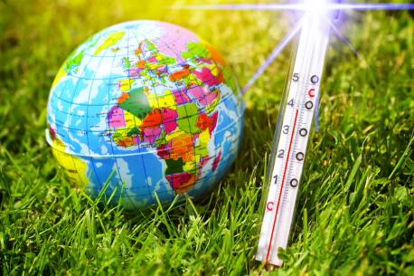 Fieberthermometer im Boden und Erdkugel, Symbolfoto Klimaerwärmung.